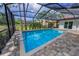 Pool area with brick pavers, ladder, screened-in enclosure and mature landscaping at 3079 Osprey Ln, Clearwater, FL 33762
