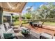 Covered patio with cozy seating area and string lights overlooking a well-maintained backyard with trees and shrubs at 30817 Pumpkin Ridge Dr, Wesley Chapel, FL 33543