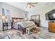 Bedroom with wood flooring and natural lighting featuring a bench at the foot of the bed and flat screen TV at 30817 Pumpkin Ridge Dr, Wesley Chapel, FL 33543