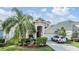 Inviting two-story tan home with landscaped front yard, featuring an attached two car garage at 30817 Pumpkin Ridge Dr, Wesley Chapel, FL 33543