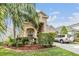 Charming tan two-story home with a well-manicured lawn and lush tropical landscaping at 30817 Pumpkin Ridge Dr, Wesley Chapel, FL 33543