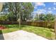 Large fenced backyard with green grass, concrete patio, and mature trees at 3806 N Tampa St, Tampa, FL 33603