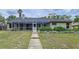 View of the home's screened-in lanai and grassy backyard with simple landscape design at 5058 Westlake Blvd, Dade City, FL 33523