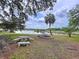 Expansive backyard featuring a tranquil lake view with seating, mature trees, and a charming firepit area at 5058 Westlake Blvd, Dade City, FL 33523