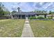 Backyard showcasing the home with screened enclosure, and concrete pathway at 5058 Westlake Blvd, Dade City, FL 33523
