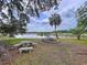 Expansive backyard featuring a tranquil lake view with seating, mature trees, and a charming firepit area at 5058 Westlake Blvd, Dade City, FL 33523