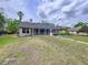 View of home and backyard, featuring a screened enclosure and lush landscaping at 5058 Westlake Blvd, Dade City, FL 33523