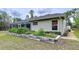 Home featuring an enclosed screened lanai, green lawn, and raised garden beds at 5058 Westlake Blvd, Dade City, FL 33523