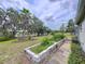 Lush backyard with manicured garden beds, mature trees, and a serene view of the adjacent lake at 5058 Westlake Blvd, Dade City, FL 33523