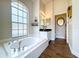 Bathroom featuring a soaking tub, large window, dark countertops and wood-look tile flooring at 5058 Westlake Blvd, Dade City, FL 33523