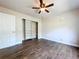 Spacious bedroom featuring wood-look floors, ceiling fan, and closet with sliding doors at 5058 Westlake Blvd, Dade City, FL 33523