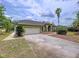 The home features a two car garage, mature landscaping, and covered entry way at 5058 Westlake Blvd, Dade City, FL 33523