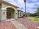 Charming single-story home with arched entryway, decorative lighting, and verdant landscaping at 5058 Westlake Blvd, Dade City, FL 33523