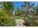 Well manicured backyard featuring lush landscaping, colorful flowers, stone pavers, and a variety of mature trees at 6507 Maiden Sea Dr, Apollo Beach, FL 33572