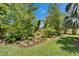 Lush backyard featuring a variety of trees, bushes, and other plants, all surrounded by a black metal fence at 6507 Maiden Sea Dr, Apollo Beach, FL 33572