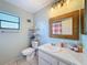 Bathroom featuring a vanity with storage, toilet, and framed mirror at 7237 Bramblewood Dr, Port Richey, FL 34668