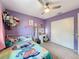 Cozy bedroom with purple walls, a colorful bedspread, ceiling fan, and closet for ample storage at 7237 Bramblewood Dr, Port Richey, FL 34668