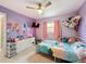 Comfortable bedroom with purple walls, a colorful bedspread, ceiling fan, and vanity and closet for storage at 7237 Bramblewood Dr, Port Richey, FL 34668