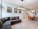Open-concept living room and dining area, featuring tile flooring, modern lighting, and comfortable sectional sofa at 7237 Bramblewood Dr, Port Richey, FL 34668