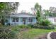 Single-story home featuring a inviting front porch, complemented by lush landscaping, and a paved stone path at 7842 15Th N Way, St Petersburg, FL 33702