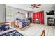 Neutral bedroom with tile floors, ceiling fan, two beds, and colorful decor at 8225 Medford Dr, Port Richey, FL 34668