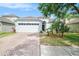 Well-maintained single-story home featuring a brick driveway, two-car garage, and manicured landscaping at 8407 Hunters Fork Loop, Ruskin, FL 33573
