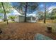 A large backyard with mature trees surrounding the home, and views of the screened-in porch and fenced in yard at 9613 River Rd, Spring Hill, FL 34608