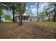 A spacious backyard featuring mature trees and the exterior of a single-story home with a screened-in porch at 9613 River Rd, Spring Hill, FL 34608