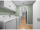Bright laundry room with appliances, overhead cabinets, and doorway to the kitchen at 9613 River Rd, Spring Hill, FL 34608