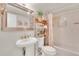 Cozy bathroom featuring a pedestal sink, framed mirror, shelving unit, and shower-tub combination at 1 Key Capri # 502E, Treasure Island, FL 33706