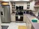 Open concept kitchen with stainless appliances, shaker cabinets, and a stylish overhead dish rack at 1 Key Capri # 502E, Treasure Island, FL 33706