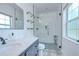 Modern bathroom with glass shower door, gray cabinets, and a large vanity mirror at 1051 44Th S St, St Petersburg, FL 33711