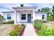 Charming home featuring a covered porch, gray door, and colorful flower beds lining the walkway at 1051 44Th S St, St Petersburg, FL 33711