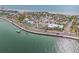 Aerial shot of coastal neighborhood showcasing a home with a pier and nearby beach, surrounded by clear, blue water at 1104 Pass A Grille Way, St Pete Beach, FL 33706