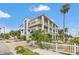 An exterior of a multi-story coastal home with white picket fence, balconies, and lush tropical landscaping near the beach at 1104 Pass A Grille Way, St Pete Beach, FL 33706