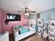 Bedroom featuring a TV, fan, wood floors, and decorative shelving for ample storage at 11314 Silverleaf Ct, Riverview, FL 33579