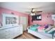 Cheerful bedroom with pink walls, wood floors, and a mirrored dresser at 11314 Silverleaf Ct, Riverview, FL 33579