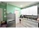 Compact kitchen with white cabinets, stainless fridge, and updated backsplash at 11314 Silverleaf Ct, Riverview, FL 33579