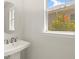 Elegant half-bathroom featuring a round mirror, pedestal sink, and a bright window at 11359 Boundless Ter, Venice, FL 34293