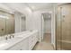 Elegant bathroom featuring dual sinks, a large mirror, glass-enclosed shower, and a walk-in closet at 11359 Boundless Ter, Venice, FL 34293