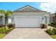 Charming home featuring a two-car garage, lush landscaping, and a brick-paved driveway at 11359 Boundless Ter, Venice, FL 34293