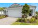 Charming home featuring a two-car garage, lush landscaping, and a brick-paved driveway at 11359 Boundless Ter, Venice, FL 34293
