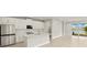 Open kitchen with stainless steel appliances, center island, tile floors, and a view of the pond through the sliding glass doors at 11359 Boundless Ter, Venice, FL 34293