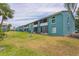 Backyard view of this charming two-story teal home showing well-maintained lawn and screened lanais at 11404 2Nd N St # 3, St Petersburg, FL 33701
