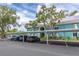 Exterior of condo building with covered parking, teal paint, landscaping, and white trim against a partially cloudy blue sky at 11404 2Nd N St # 3, St Petersburg, FL 33701