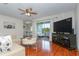 Bright living room with hardwood floors, a ceiling fan, tan sofa, and sliding glass doors to an outdoor balcony at 11404 2Nd N St # 3, St Petersburg, FL 33701