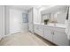 Bright bathroom featuring double sinks, white cabinets, and neutral tiling at 118 Leisure Pl, Rotonda West, FL 33947
