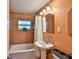 Cozy bathroom with a shower-tub combo, a pedestal sink, and warm colored tiles at 1500 Robinson N Dr, St Petersburg, FL 33710