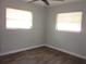 Empty bedroom with hardwood flooring, a ceiling fan, and two windows with blinds for natural light at 162 Sw Lincoln N Cir, St Petersburg, FL 33703