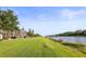 Scenic backyard with a lush green lawn leading to the waterfront, offering serene views and access at 1768 Lago Vista Blvd, Palm Harbor, FL 34685
